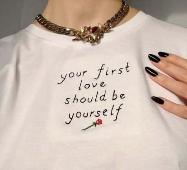 foto de camiseta branca que foi bordada à mão com a frase your first love should be yourself