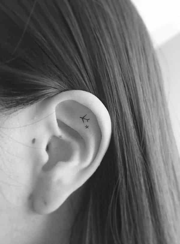 pequena tatuagem de avião na orelha