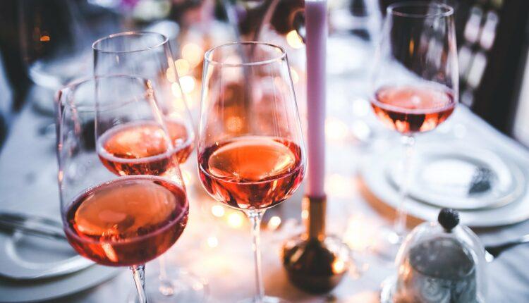 mesa de jantar com toalha e louças brancas e taças de vinho rosé