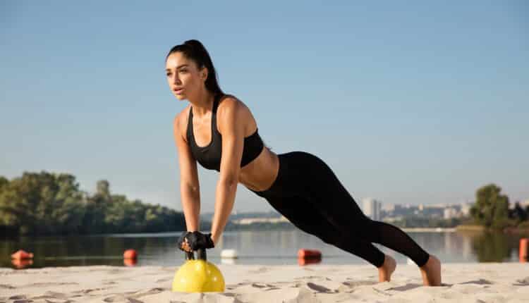 Young healthy female athlete doing workout at the beach