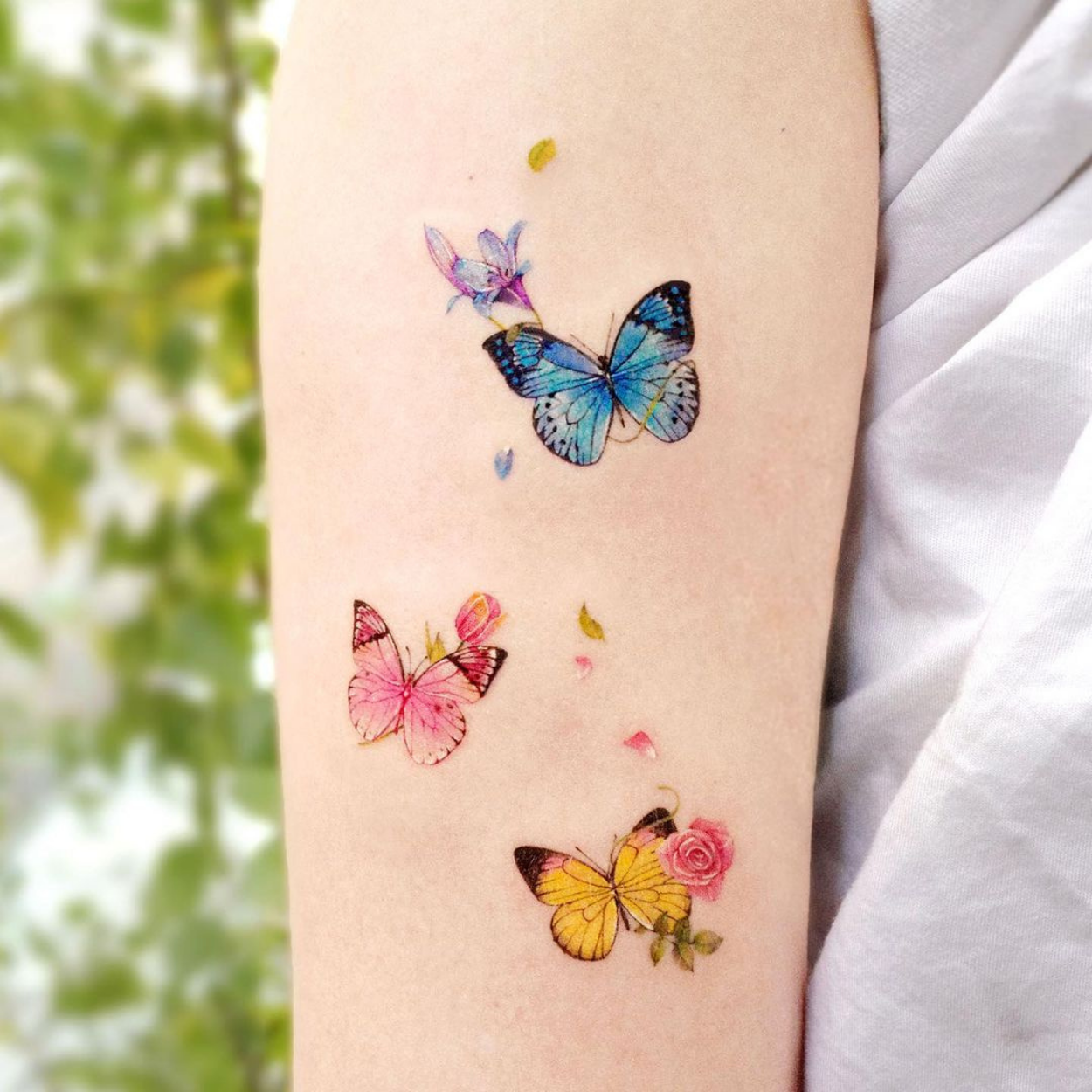tatuagem de três borboletas delicadas coloridas