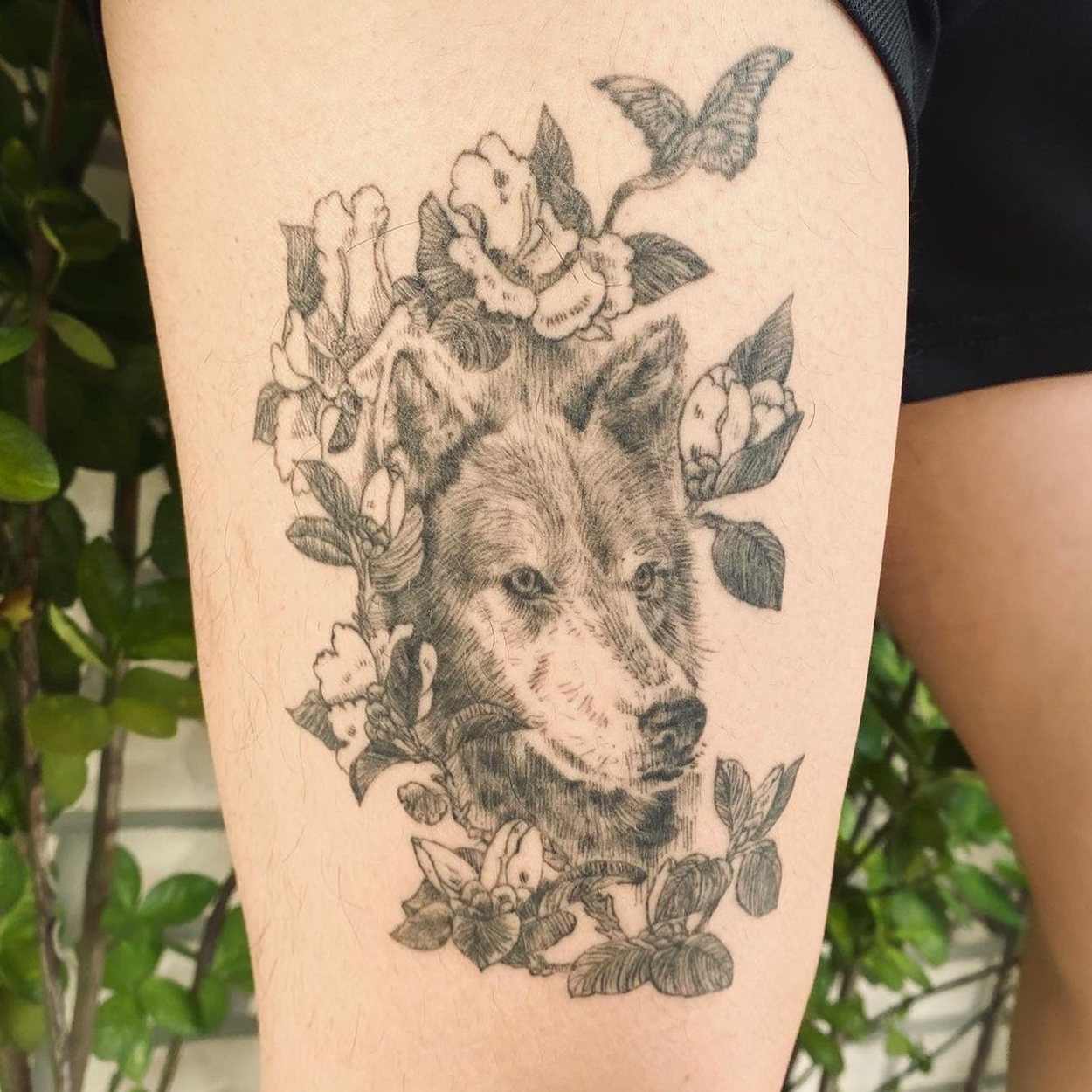 Tatuagem de lobo com flor na coxa