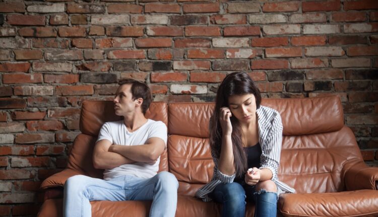 Frustrated upset couple after quarrel sitting on sofa at home